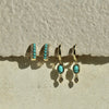 Turquoise earrings on a textured beige surface