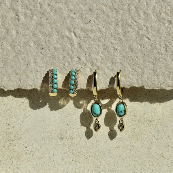 Turquoise earrings on a textured beige surface