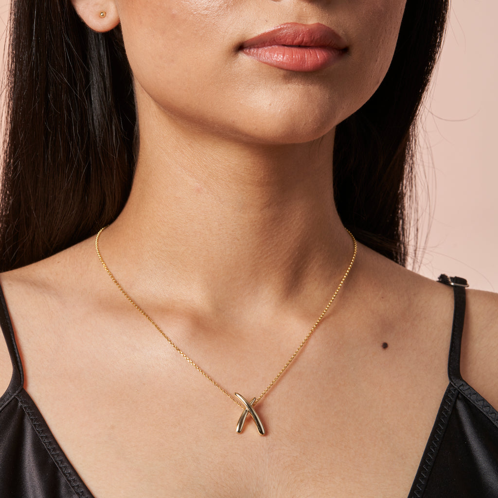 woman wearing Crossover X Gold Pendant by Ixora Jewelers