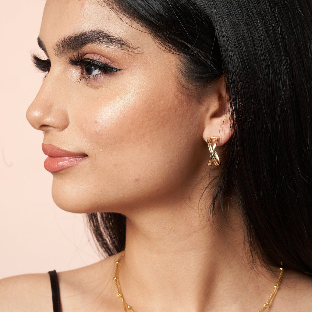 woman wearing Crossover Gold Earring by Ixora Jewelers